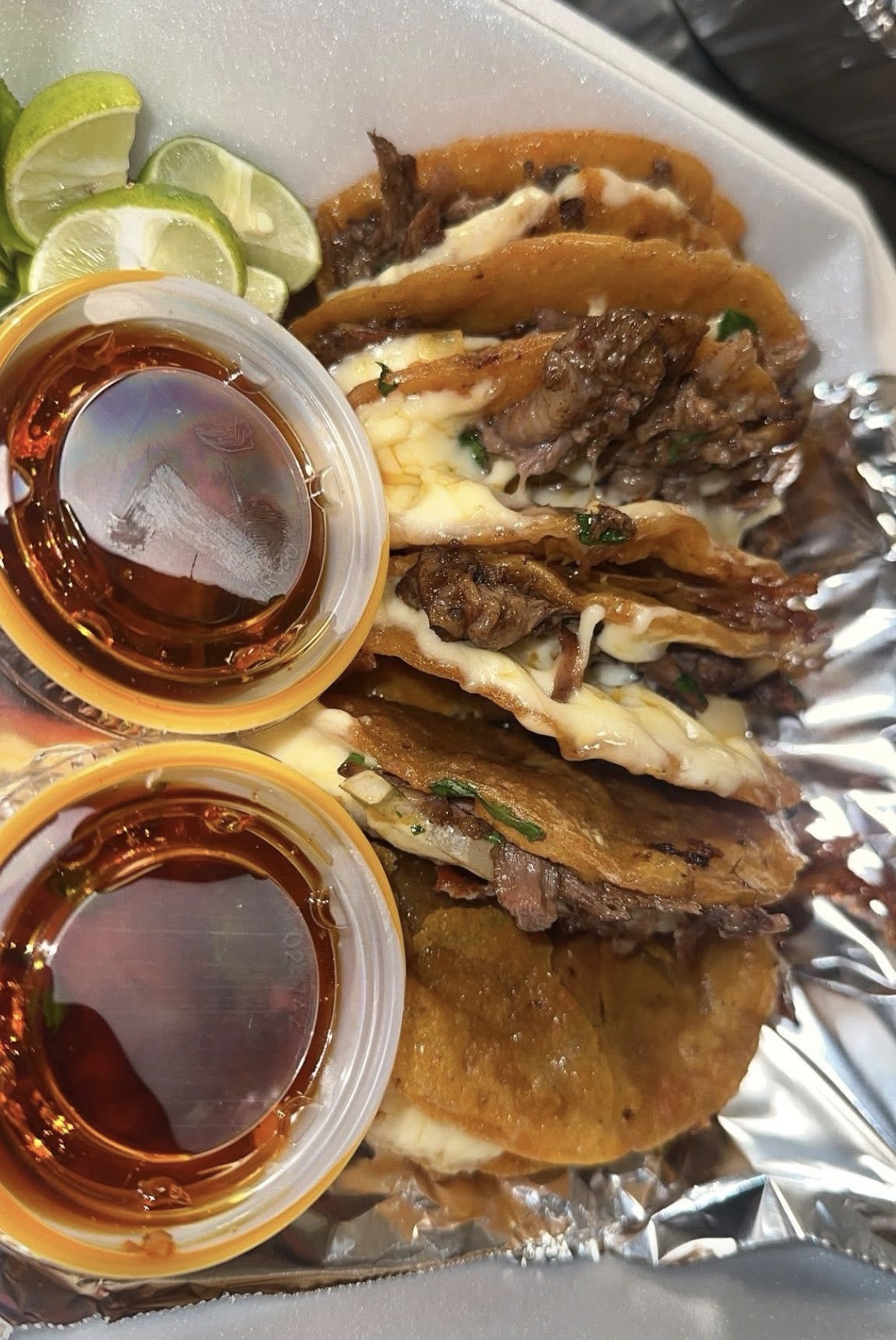 Close-up of a Vatos Tacos street taco with steam, cilantro, onion, and lime